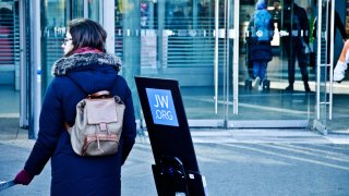 A female Jehovah's Witness member on an outreach programme outside the entrance of Berlin Hauptbahnhof (Main Train Station)  - Germany.