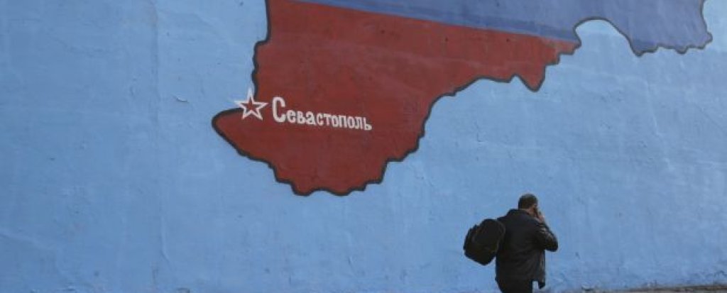 A man passes a mural showing a map of Crimea in Russian national colors on a street in Moscow