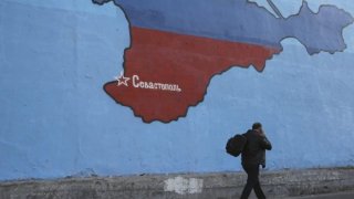 A man passes a mural showing a map of Crimea in Russian national colors on a street in Moscow