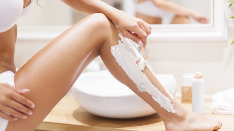 Close up of woman shaving legs in bathroom