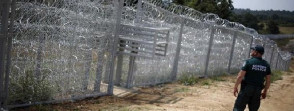 A Bulgarian border policeman stands in front of a barbed wire fence on the Bulgarian-Turkish border
