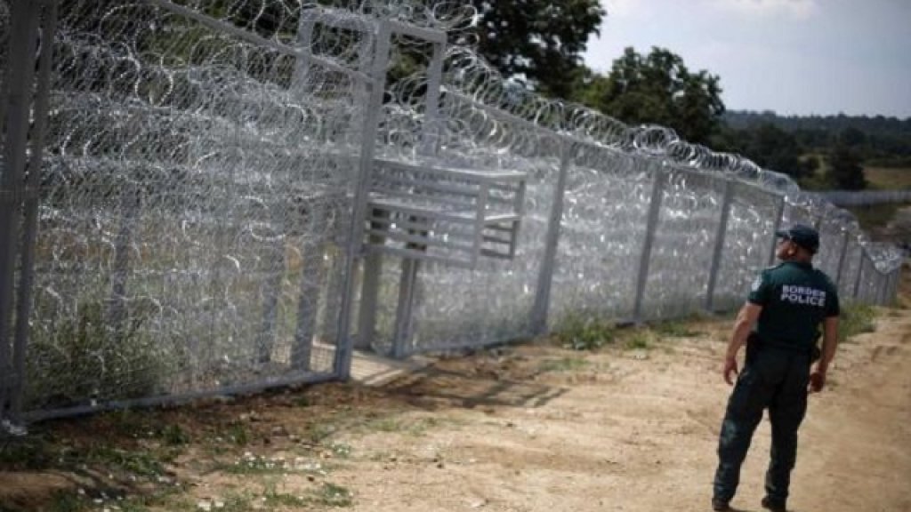 A Bulgarian border policeman stands in front of a barbed wire fence on the Bulgarian-Turkish border