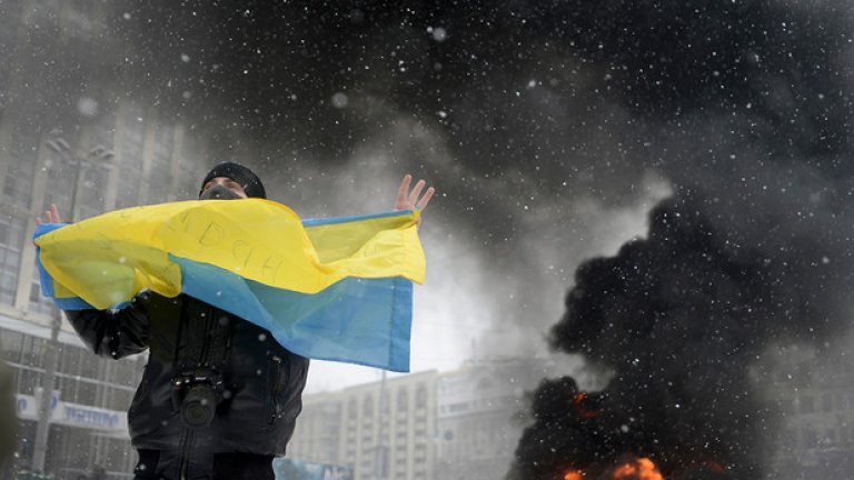 22 януари 2014 година. Мъж развява украинското знаме, докато зад него се надига дим по време на сблъсъка между полицията и проевропейски настроените демонстранти в Киев. Същия ден украинският президент Виктор Янукович  прие да се срещне с тримата основни лидери на опозицията и да разговарят за кризата, довела до яростните сблъсъци между демонстранти и полиция.
Снимка: Reuters/ Maks Levin/ Макс Левин