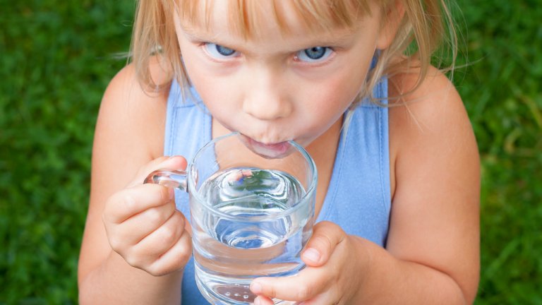 Child drinking water outdoors