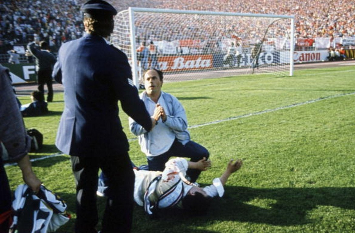 Кървавият финал на „Хейзел”

На 29 май 1985 г. се случва една от най-големите трагедии в историята на футбола. 39 запалянковци намират смъртта си в сблъсъците по трибуните на стадион „Хейзел” в Бюрксел, където трябва да се играе финалът за Купата на европейските шампиони между Ювентус и Ливърпул. Сред загиналите са 32-ма италианци, четирима белгийци, двама французи и гражданин на Северна Ирландия. 
Да проведеш футболна среща след такова масово убийство си е жив цинизъм. Но с аргумента, че ако мачът не се състои, ще стане още по-страшно, властите в Брюксел и УЕФА решават да се играе. Нещо повече – скриват от затворените в съблекалните футболисти от двата отбора истинските мащаби на трагедията и им казват, че смъртните случаи са само няколко. 
„Абсурдно беше да излезем, ако знаехме, че има 39 загинали. Казаха ни, че има само няколко смъртни случая”, свидетелства Мишел Платини в книгата си „Говорим за футбол”. Самият той си навлича гнева на европейската футболна общност, след като започва бурно да се радва при гола си от дузпа за Ювентус, донесъл победата с 1:0.
Възмущението срещу УЕФА и нейният президент Жак Жорж е огромно. Не само заради решението да проведат финала, докато труповете на загиналите още не са изстинали в моргата. Централата прави гаф и с продажбата на билети, заради който трибуната в близост до хулиганите от Ливърпул се оказва пълна с италиански тифози.