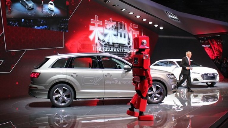 Робот или човек?
Audi използва човек, предрешен като робот, за да привлече вниманието към хибридните си предложения в Шанхай. Скоро на местния пазар ще се появи версия на Q7 e-tron с 2-литров бензинов турбо мотор, електромотор и Quattro задвижване. Шефовете на марката Руперт Щадлер и Улрих Хакенберг не оцениха високо идеята човек да се представя за робот.