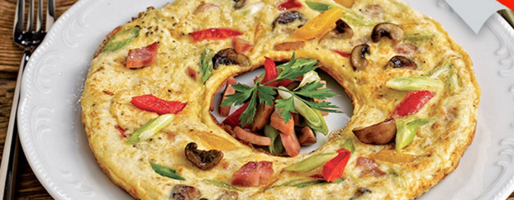 1. Италианска Фритата с шунка и зеленчуци
• Нарязани на ситно: 3 стръка пресен лук, 2 чушки, зелена и червена 100 г шунка, 50 г меко козе сирене, 8-10 гъби • 10 яйца • магданоз • зехтин • пипер • сол
Затоплете 1-2 супени лъжици зехтин в универсален тиган Деличия и запържете лука на бавен огън. Добавете шунката и я запържете леко. Прибавете гъбите и чушките, поставете капак и гответе, докато продуктите омекнат. Разбийте яйцата със сол и пипер. Изсипете ги върху сместа от шунка и зеленчуци. Намалете температурата и поръсете отгоре с нарязаното сирене. Поставете капак и гответе, докато фритатата се изпържи. Сервирайте с украса от пресни зеленчуци и магданоз.