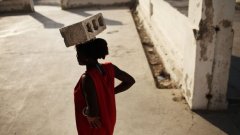 Хаитянка върви с тухла на главата си покрай разрушена от земетресението катедрала