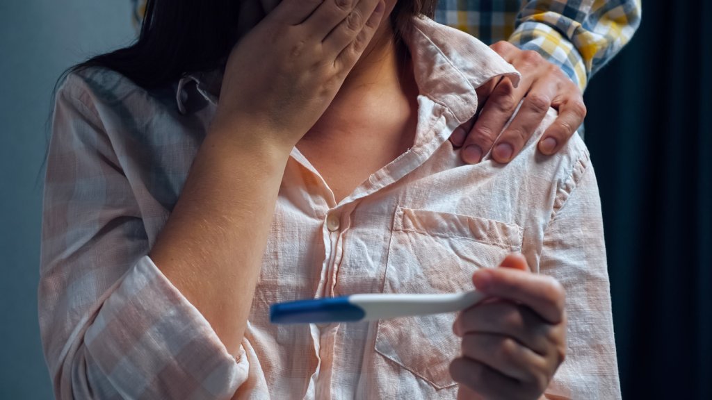 woman with pregnancy test. The man stays behind tense wife