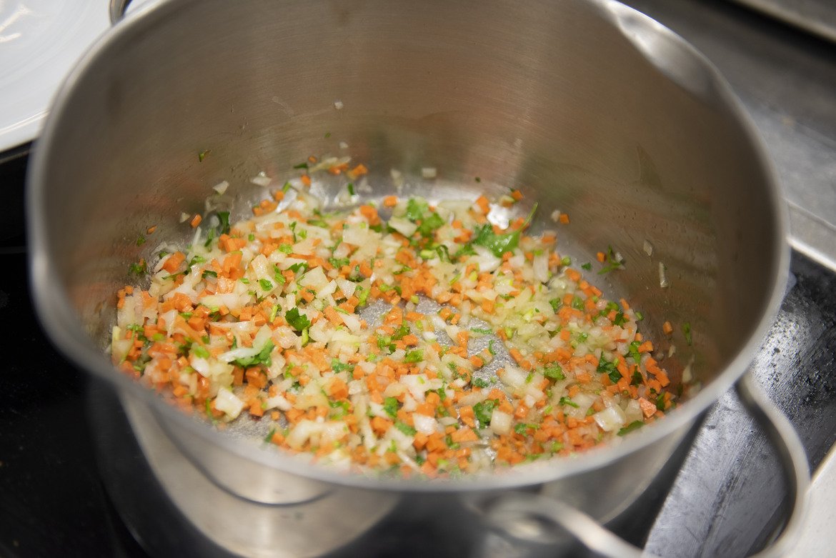 4. Загравяме голяма тенджера с дебело дъно на среден огън.

Добавяме олио или зехтин, малко масло и слагаме лука, морковите, целината, чесъна (цял, необелен), мащерката и дръжките на магданоза, нарязани на ситно.
Запържваме около 15 минути на нисък пламък, за да може морковите да пуснат цвета си.
Chefs Tip: За по-интересен вкус на този етап може да сложите малко куркума, шафран или къри, както и малко лимонова кора.