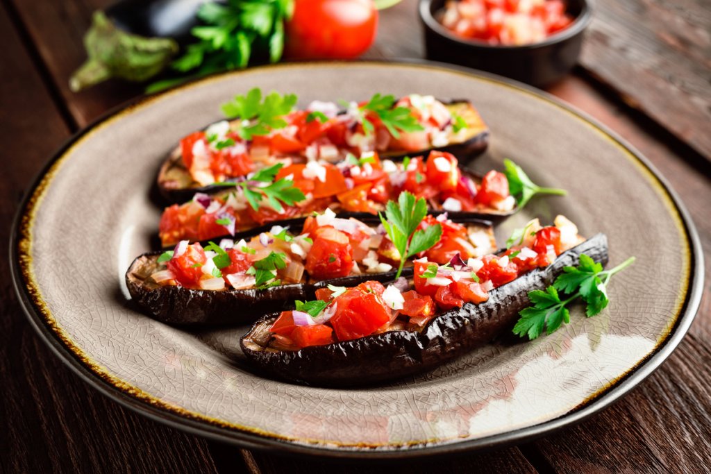 Пълнени патладжани с домати и фетаЗасищащите патладжани нямат нужда от много продукти, за да са вкусни. По-малки патладжани според броя на гладните се разполовяват и издълбават. Поръсват се със сол и малко зехтин и се оставят настрана. През това време в дълбок тиган се запържват глава лук, няколко скилидки скълцан чесън, вътрешността на патладжана и 500 грама домати на кубчета.
Подправя се със сол, пипер, риган и босилек, а когато доматите омекнат и сместа се сгъсти се прибавят и 200-300 грама сирене фета на кубчета. Патладжаните се пълнят и се пекат на 170 градуса до покафеняване. Можем да използваме и чери домати, както и друг вид сирене според наличността.