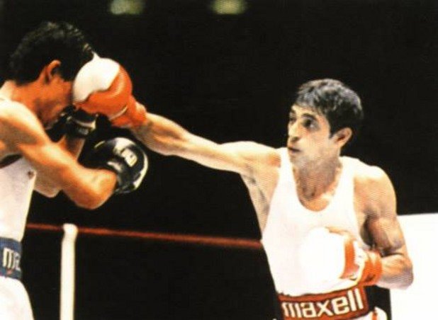 Ивайло Маринов пуши цигара и бие Карбахал

Преди да спечели титлата в Сеул `88, Ивайло Маринов (48 кг.) е спрян да участва в други две големи състезания. Заради бойкота на олимпийските игри в Лос Анджелис през 1984 г. изпуска сигурна титла, а две години по-късно го свалят от самолета точно преди излитането за световното първенство в Рино с аргумента, че може да избяга в САЩ заради възродителния процес и смяната на истинското му име, което е Исмаил Мустафов. В Сеул варненецът помита първите си четирима противници с по 5:0, но на финала се пада с „американското торнадо” Майкъл Карбахал. Точно преди двубоя Маринов нещо се смущава и излиза навън да изпушат по цигара с пратеника на БТА и боксов експерт Валентин Серафимов, който успява да го окуражи само за няколко минути. „Гледай сега какво ще го направя този американец!”, отсича Ивайло след последното смукване от фаса. Резултатът е 5:0 за новия олимпийски шампион от България. След мача някой колекционер на реликви открадва гащетата му от хотелската стая. За титлата варненецът получава орден „Георги Димитров”, лека кола „Волга” и 2500 долара, които по собствените му признания пропива с приятели.
