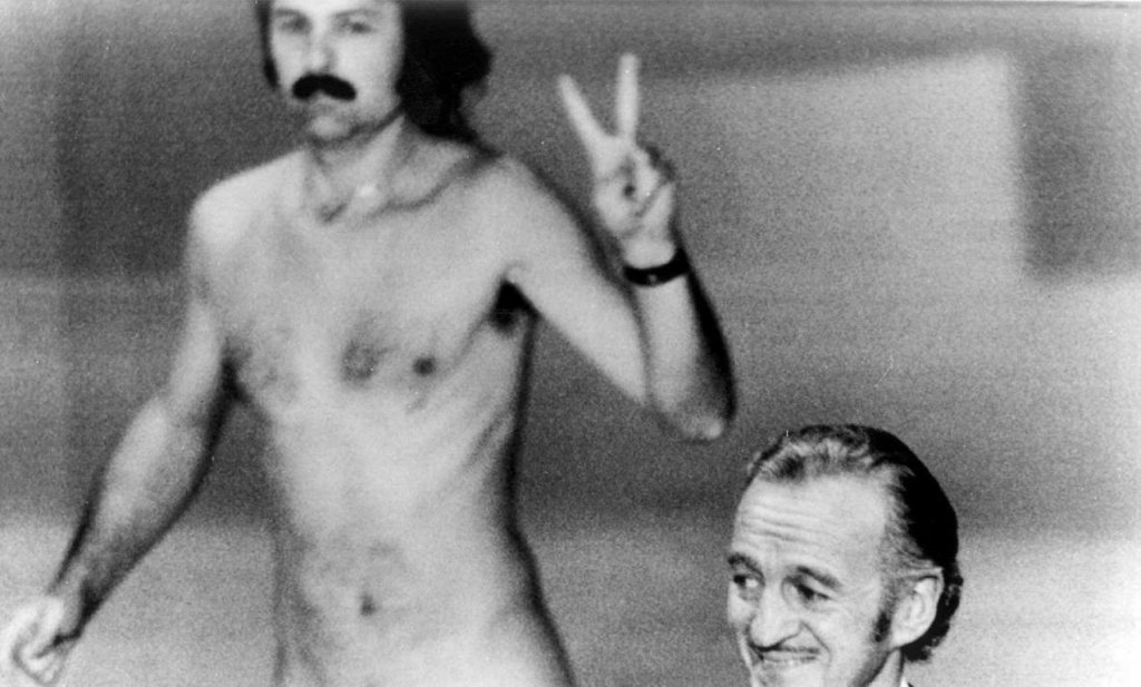 През 1974 година водещият Дейвид Нивън представя на сцената Елизабет Тейлър, която да връчи награда на следващия носител на „Оскар”. Междувременно обаче зад гърба им пробягва гол активистът Робърт Опел, който размахва знак за мир и...не само това. Няколко