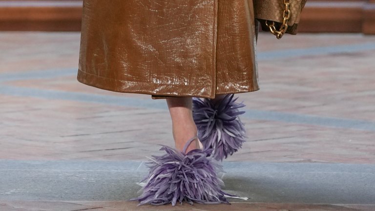 Мекота, която не е сантиментална
Косъмът и пухкавите елементи се появяват не за украса, а за настроение и комфорт. Тези детайли носят усещане за топлина и интимност, без да превръщат обувките в домашен аксесоар. Напротив – използвани премерено, те добавят характер и визуален контраст към по-груби силуети и тежки подметки.