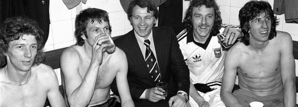 Минути след края на същия мач - кадър от съблекалнята на победителите. Сър Боби Робсън, мениджър на Ипсуич, пие по бира с играчите си за класирането на финала - първо и единствено в историята на клуба. Там Ипсуич бие Арсенал с 1:0.