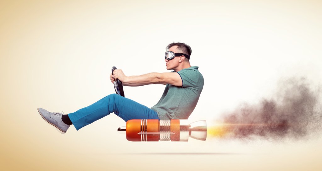 Cool man in casual clothes with goggles holds a steering wheel in his hands while driving an alternative vehicle, on yellow background.