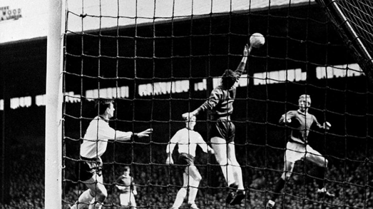 Мач от Първа дивзия на "Олд Трафорд" през април 1965-а. Денис Лоу, известен като Краля, стреля с глава, но топката минава над гредата на вратата на Ливърпул, пазена от Томи Лоурънс. Юнайтед печели с 3:0 по пътя си към титлата през този сезон под ръководството на Мат Бъзби. Сезонът е паметен и за Ливърпул, който вдига ФА къп за първи път с Бил Шенкли за мениджър на скамейката.