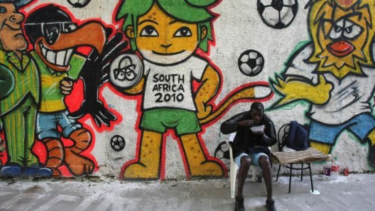 Жител на квартал "Вила Изабел" в Рио де Жанейро обядва на улицата, украсена с графити по случай световното първенство по футбол в Южна Африка
