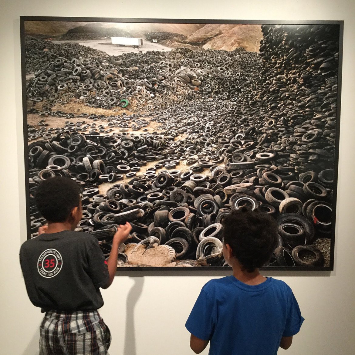 Деца гледат една от най-известните снимки на Едуард Бъртински с планините от стари гуми