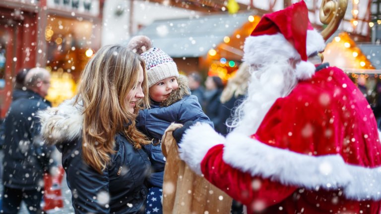 Little toddler girl with mother on Christmas market.