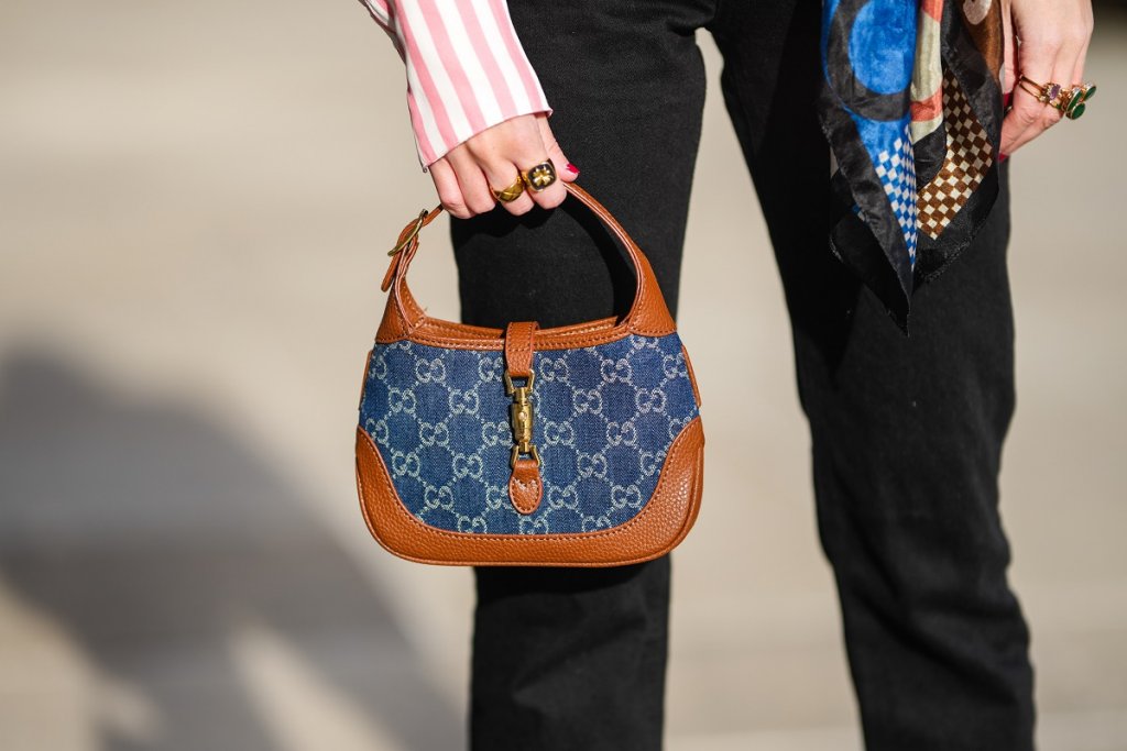 Jackie на Gucci
Чантата на Gucci във формата на полумесец от кафява кожа на глиган се появява на пазара през 1961 г., като е замислена за унисекс аксесоар. През 70-те обаче Джаки Кенеди Онасис започва да я носи в по-небрежен стил и понеже пресата се пълни с нейни снимки, от Gucci решават да кръстят чантата на бившата първа дама на САЩ.