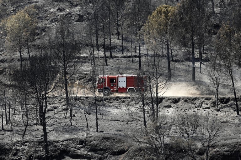 Пожарна преминава през опостушен от огъня район край село около Барселона.