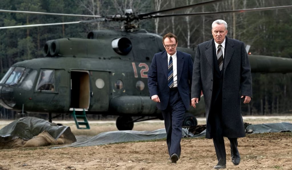 1. “Чернобил” (2019 г.)
Оценка в IMDb: 9,3 от 10 звезди
Оценка в Rotten Tomatoes: 97% одобрение
Къде да гледате: в HBO Max
Минисериалът пресъздава едно от най-тежките технологични бедствия в историята – ядрената авария в съветската АЕЦ „Чернобил“ през април 1986 г.
Сюжетът проследява както събитията непосредствено след експлозията, така и усилията на учените, пожарникарите и обикновените хора, които се опитват да овладеят катастрофата – често с цената на собствения си живот. Особен акцент е поставен върху опитите на съветската власт да прикрие истинските мащаби на бедствието и последиците от него.