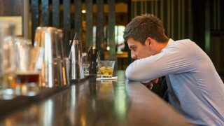 Lonely Hispanic businessman sitting at bar