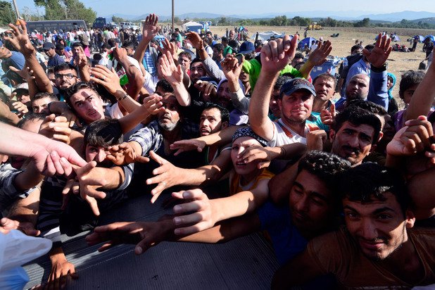 Мигранти чакат помощи от "Каритас" на границата между Гърция и Македония. Вълната от хиляди новопристигнали бежанци не намалява.