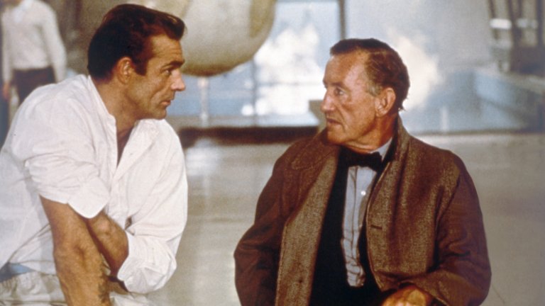 Иън Флеминг
Флеминг е роден в богато семейство през 1908 г., но кариерата му не започва добре, защото той се проваля на изпита за британското външно министерство. Комбинацията от връзки и късмет му помагат да не се озове на фронта през Втората световна война и, вместо това, той получава служба на висок административен пост във военноморското разузнаване. В новото си амплоа Флеминг демонстрира размах и въображение, които му печелят кредит на доверие и той постепенно е включен в разработването на шпионски планове и операции. Бъдещият писател очевидно се справя добре, защото през 1941 г.  е част от британския екип, който помага за създаването на разузнавателната мрежа, която в последствие ще прерасне  в ЦРУ.След края на Студената война Иън Флеминг се заселва за постоянно в Ямайка и през 1953 г. пише книга на име "Казино Роял". Героят в творбата е наречен на орнитолога Джеймс Бонд, който пък е автор на книгата "Птиците на Западните Индии", намираща се в библиотеката на Флеминг. Авторът твърди, че просто е търсил повече от обикновено име за своя персонаж, а иронията на съдбата е такава, че години по-късно това име остава емблематично.