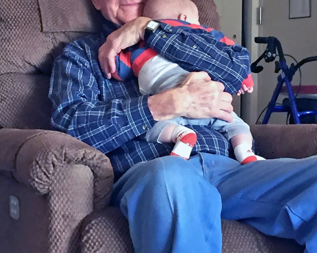 Щастлив дядо, който гушка своето правнуче