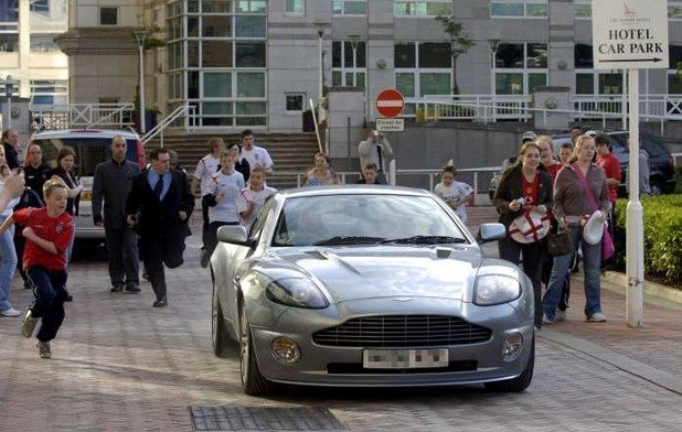 Деца в екипи на Англия преследват Aston Martin Vanquish S, шофиран от Уейн Рууни. Новият рекордьор по голове за националния плати над 200 000 лири за колата с екстрите.