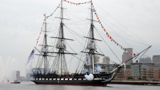 USS Constitution fires a 17-gun salute.