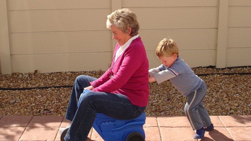1280px-Child_pushing_grandmother_on_plastic_tricycle