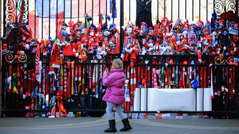 Момиченце минава покрай портите на стадион "Анфийлд", които във вторник изглеждаха така - обсипани с шалчета на какви ли не отбори.