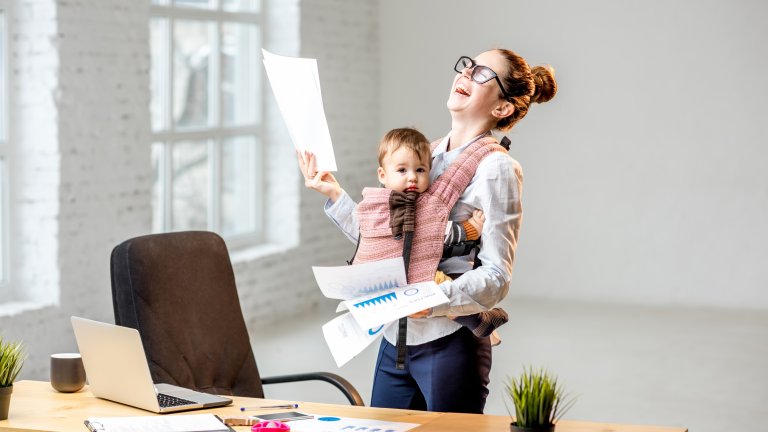 Businesswoman with her baby son working with documents at the office