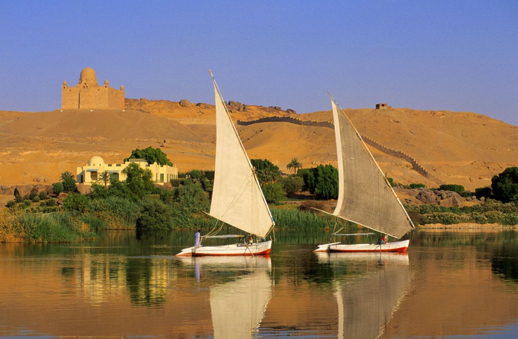Egypt, Upper Egypt, Aswan, feluccas on Nile River, Aga Khan Mausoleum in the background