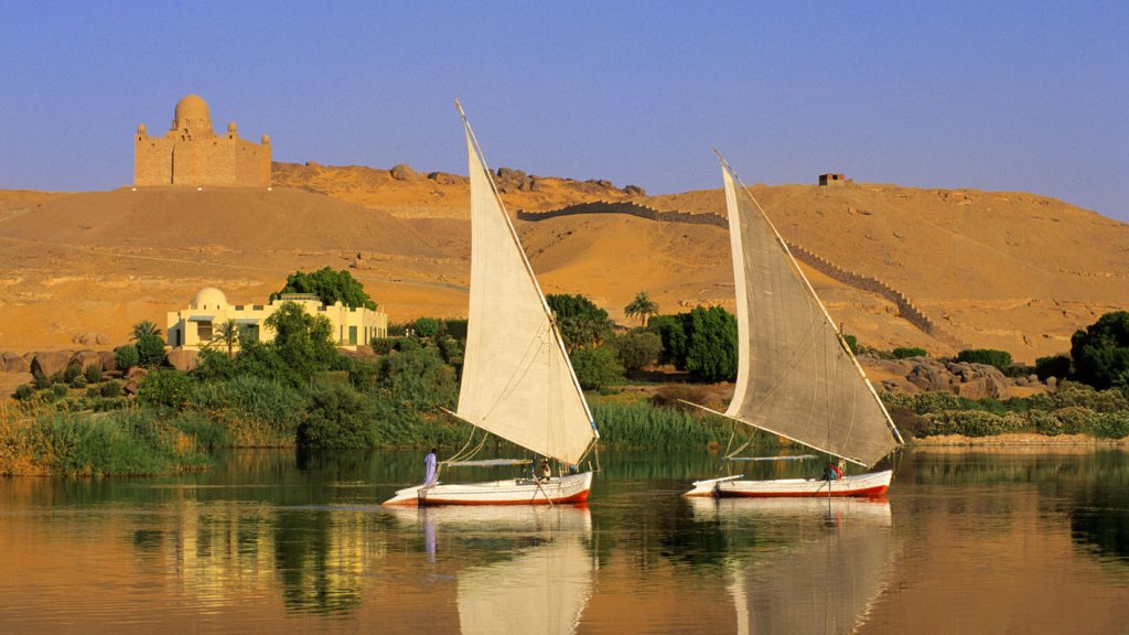 Egypt, Upper Egypt, Aswan, feluccas on Nile River, Aga Khan Mausoleum in the background