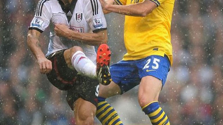 Димитър Бербатов опитва да преодолее Карл Дженкинсън от Арсенал в мача, игран под непрестанен проливен дъжд в Лондон.