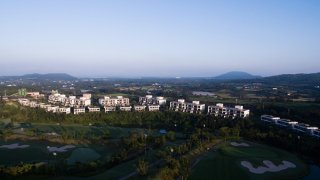 The Teddy Palace apartments, developed by Jeju China Castle Ltd. (JCC), stand next to a golf course in this aerial photograph taken above Seogwipo in Jeju, South Korea, on Sunday, June 28, 2015. South Korea?s 15 trillion won ($13.3 billion) extra budget will channel money to the medical and tourism sectors as the Park administration seeks to cushion the impact of a deadly respiratory disease. Photographer: SeongJoon Cho/Bloomberg