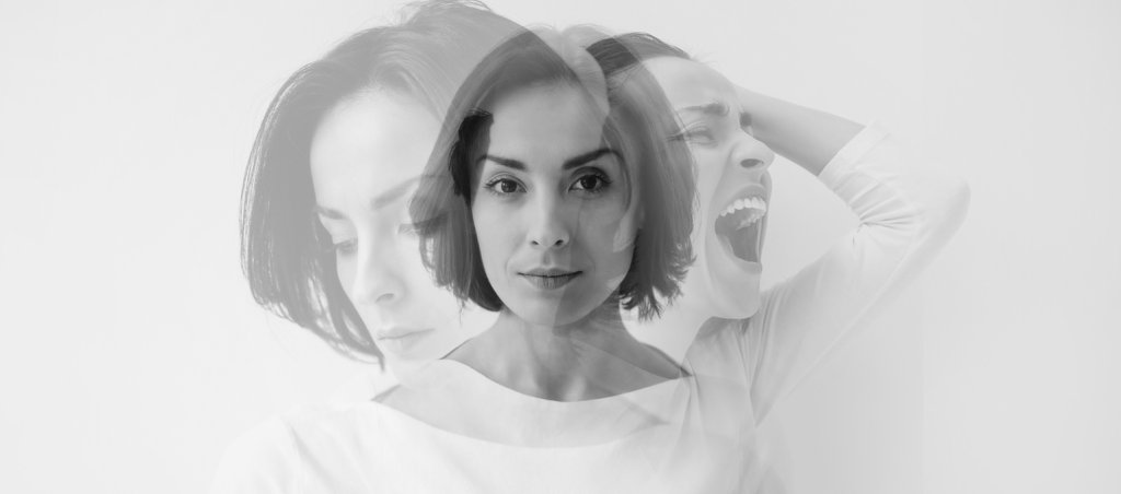Multiple identities. Close-up photo of a young pretty brunette girl who is looking in the camera while internally suffering from a dissociative identity disorder. Double exposure.