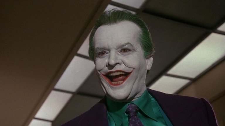 2. Джак Никълсън (Batman, 1989)
Така стигаме до филма на режисьора Тим Бъртън от 1989-а, който отново събуди интереса на масовата публика към Човек-прилеп. Огромен плюс на този филм е Джак Никълсън, който има опит в това да играе психопати. Неговият Жокер тук има предистория - той е гангстера Джак Нейпиър, който е предаден от собствения си шеф и след среща с Батман пада в опасни химикали. Те отнемат разсъдъка му и му придават характерния за Жокера външен вид.
Този Жокер визуално прилича на онзи, изигран от Ромеро през 60-те и също не е лишен от чувство за хумор. В същото време е непредсказуем психопат, склонен да убие и най-близките си съдружници или да обезобрази и най-красивата жена.