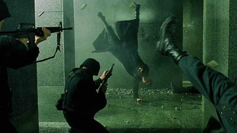 “Матрицата” - Престрелката във фоайето
“Матрицата” е толкова революционен и запомнящ се филм, че практически всеки един момент от него е велик сам по себе си. Това важи особено много за екшън сцените, които правят истинска революция в киното заради въвеждането на цял куп нови визуални ефекти.
Един от запомнящите се моменти, освен ръкопашните схватки, е престрелката във фоайето на бизнес сградата, когато Нео и Тринити отиват да спасят Морфей от плен. В нито един момент двамата не изглежда да бъдат в опасност, а целият акцент е поставен върху абсолютното им превъзходство над охраната на фона на пороя от олово и падащи отломки. Всичко това е заснето с няколко подхода на забавения кадър, които после започват да бъдат широко прилагани и в други филми.