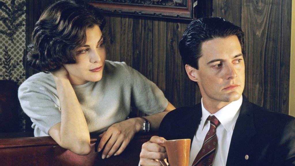 "Туин Пийкс" (Twin Peaks)
Нека скандалите започнат... сега! Легендарният сериал на Дейвид Линч и Марк Фрост до ден-днешен разделя зрителите на лагери - едни харесват първите два сезона, други - и третия, а има и такива, които не могат да понасят нищо с името "Туин Пийкс". Но нека бъдем честни - първите осем епизода сякаш са най-стегнати, обмислени и увлекателни. От самото начало пленяват зрителя с мистерията "Кой уби Лора Палмър?", представят невинния, но смел ФБР агент Купър (Кайл Макклоклан) и редица други шарени персонажи, но най-вече успешно комбинират трилър елементи с абсурдна комедия, а на места - и тийнейджърска драма.
Тогава обаче се намесват телевизионните шефове, които настояват мистерията около убийството на Лора да бъде разкрита по-бързо, а това прогонва зрителите, вместо да ги задържи. Вторият сезон е много по-разпилян и не така интересен, а третият, който Линч и Фрост създадоха през 2017 г., е провокативен експеримент, но с тона и монотонността си може да накара някои по-нетърпеливи зрители да ругаят пред екрана.