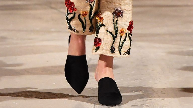 Официалните, но и лежерни лоуфъри
Ако до вчера свързвахте лоуфърите единствено с есенната униформа на софийските хипстъри или с гардероба на дядо ви, когато отива до пощата, време е за ъпдейт. Пролетта на 2026-а реши, че е крайно време да освободи петите ни от робството на кожата и резултатът е тук: retro clog vibe среща класическата обувка в нещо, което прилича на хибрид между луксозен чехъл и официален лоуфър.
Този „рефреш“ всъщност е голямата новина от ревютата на Виктория Бекъм и Bottega Veneta. Дизайнерите ни убеждават, че сгънатата пета и силуетът „без гръб“ са точно това, от което се нуждаем, за да изглеждаме хем излъскани за офиса, хем достатъчно лежерни за аперитив на слънце