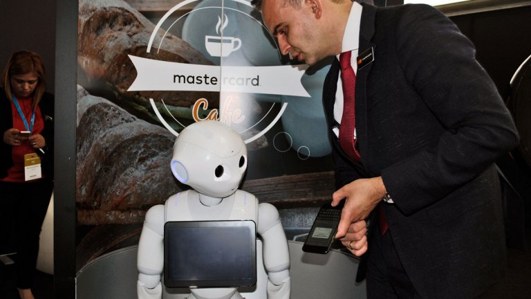 Хуманоидният робот Pepper и изпълнителният директор на Mastercard за Балканите Артур Туремка (вдясно)