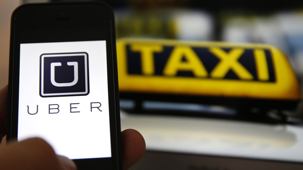 An illustration picture shows the logo of car-sharing service app Uber on a smartphone next to the picture of an official German taxi sign