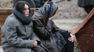 Tired women are sitting in the cold. Refugees. Refugees