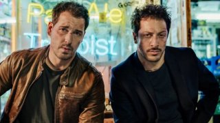 Добрите сериали не идват само от САЩ и Великобритания и в Netflix има достатъчно доказателства за това. В галерията сме ви подбрали някои от най-добрите и интересните сериали извън доминацията на англосаксонската култура, които могат да се намерят - от Германия, Франция, Индия, Корея и къде ли още не.  
Германия - Dogs of Berlin
Не е като вече да не сме ви говорили достатъчно за Dark и това колко велик сериал е. Затова нещо друго - Dogs of Berlin. Мрачно шоу за криминалния свят на германската столица Берлин - корупция сред полицията и борбата с организираната престъпност както сред турското малцинство, така и сред неонацистите. А когато един млад и обещаващ футболист от турски произход е убит без видима причина, това може да разпали сериозно етническо насилие в Берлин. И единствените, които могат да го спрат, са двама полицаи - млад турчин и един твърде обвързан с криминалния свят германец. Сериалът е само един сезон, но си заслужава напълно гледането.