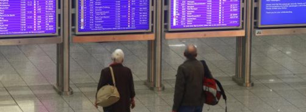 Passengers look at flight information displays during a strike at Frankfurt airport